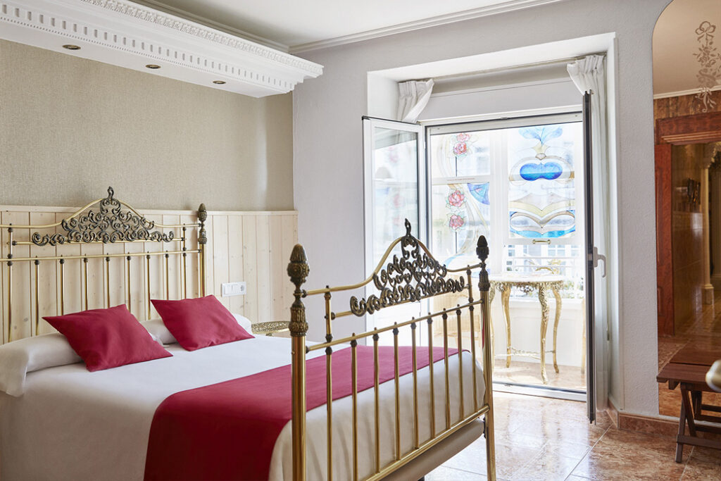 Hotel Dato room with ornamental bed frames, burgundy textiles and stained glass