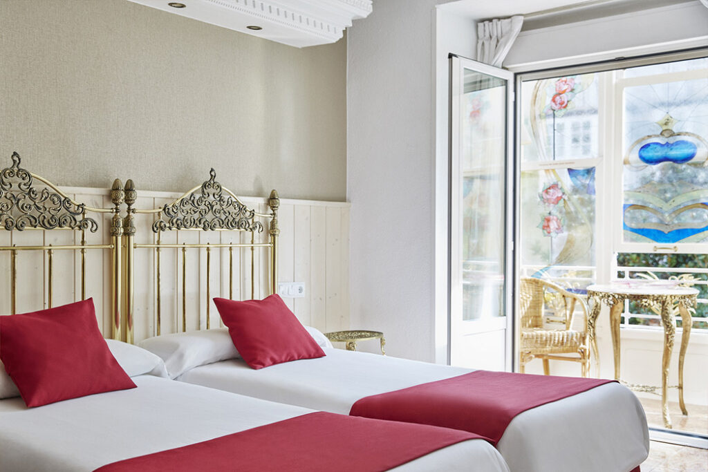 Habitación de Hotel Dato con cabeceros ornamentales, textiles burdeos y vidriera